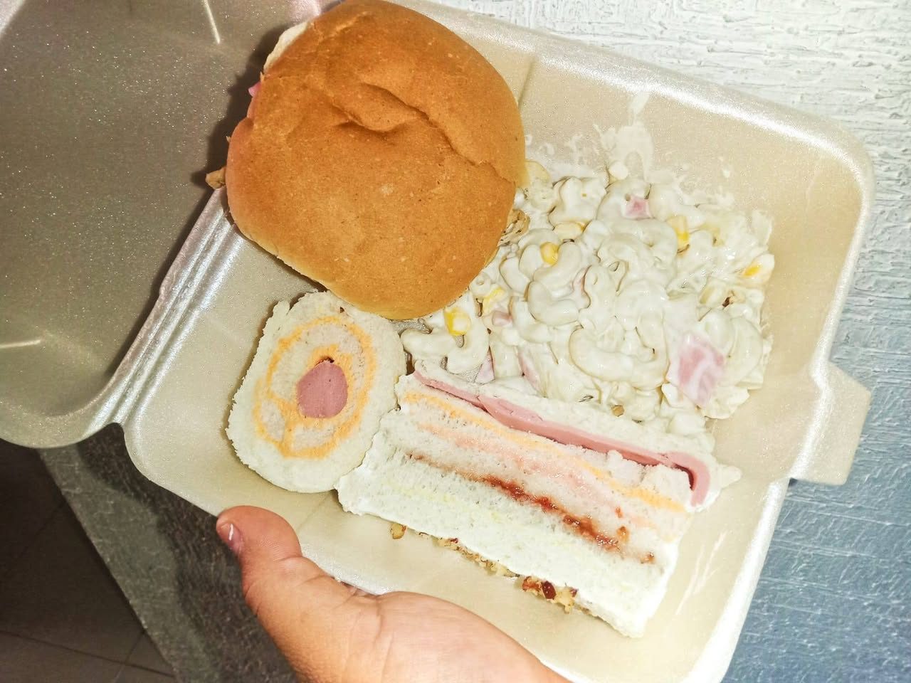 Pan con relleno crema, jamón y cebolla morada sobre plato blanco con decoracion de flores amarillas.