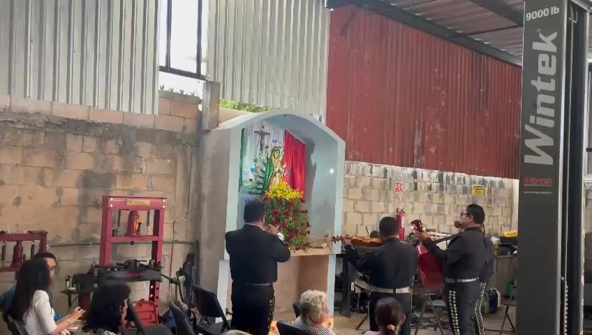 Evento musical con grupo tocando guitarra y bajo frente a bandera mexicana.